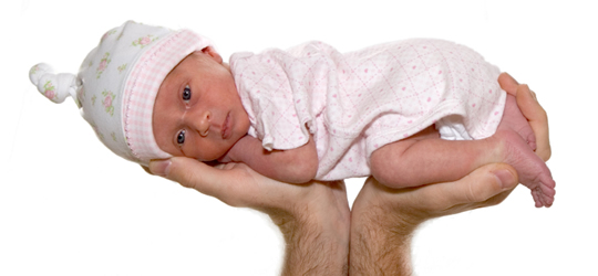 A premature baby resting on a parent's hands